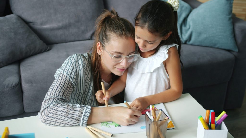 Mère et fille dessinent ensemble à une table.